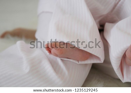 
tender bare feet of a newborn baby in pink pajamas in a happy childhood