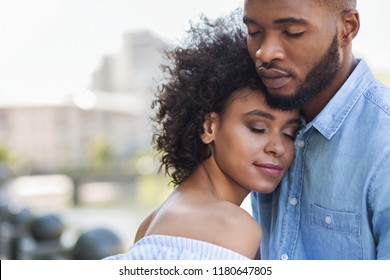 Tender black couple hugging with closed eyes outdoors