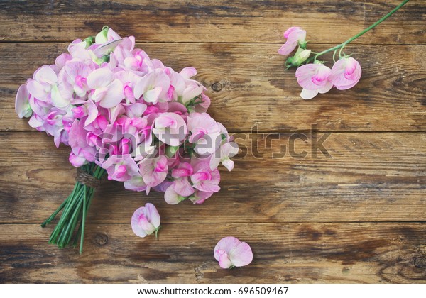 Tender bouquet of sweet peas, on wooden table,\
vintage style, top view