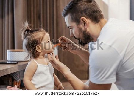 A tender father is giving a medicine to his baby girl.