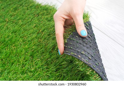 Tender female hand touching an artificial grass roll