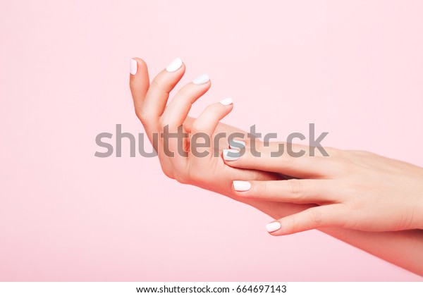 Tender hands with perfect\
blue and pink manicure on trendy pastel pink background. Place for\
text.