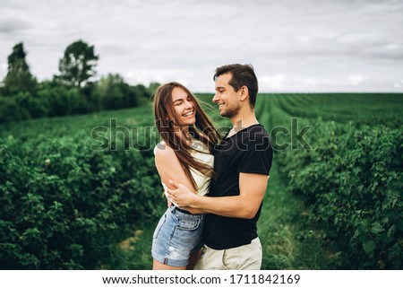 A tender loving couple walking in a field of currant. Man whirls woman in her arms. Love story.