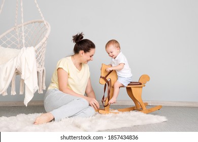 Tender Mom And Son. Child Sitting On Ride On Toy In Playroom. Toddler Baby Boy Riding Swinging On Rocking Chair Toy Horse.