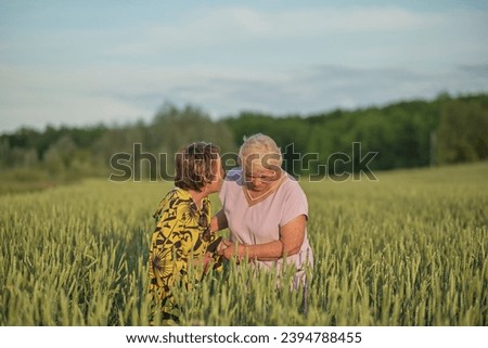 A tender moment as one woman teases the other in a field at sunset. Represents the value of humor and companionship in senior years.