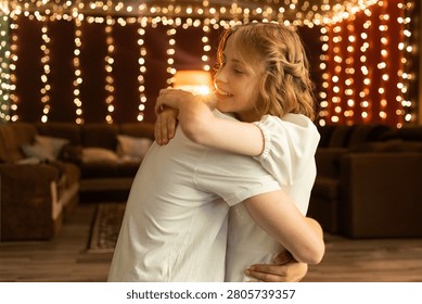 A tender moment shared between two people, their embrace illuminated by a warm, festive glow