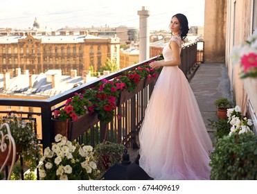 Tender outdoor full length portrait of young beautiful elegant woman with brunette hair and hairstyle standing and posing in long fluffy pink dress at summer terrace on sunny summer day - Powered by Shutterstock