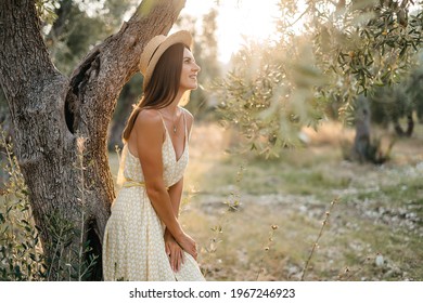 Tender portrait of beautiful brunette woman in beautiful sunlight. Woman in yellow summer linen dress in olive tree garden. Natural beauty.Travel to Italy, summer vacation. High quality photo