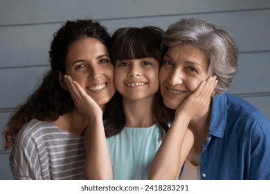 Tender relationship. Portrait of bonding multi generational family of older grandma young mom and little preteen daughter grandkid look at camera touch cheeks with love affection feel happy together - Powered by Shutterstock