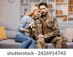 Tender scene on sofa in cozy room, where woman, bouquet in hand, leans against her husband, who