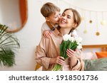 tender son kisses the happy mother and gives her a bouquet of tulips, congratulating her on mother