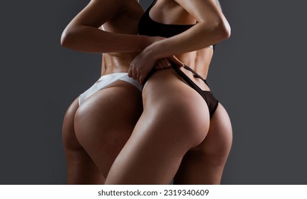 Tender two romantic girls in sexy lingerie. Sexy women posing in erotic lingerie in studio. Perfect young woman in a beautiful lace underpants. Close up of buttocks, female butt in panty.