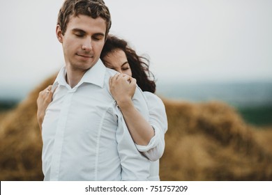 Tender woman hugs her man from behind standing on the field