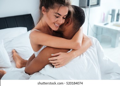 Tender young couple sitting and embracing in bed at home