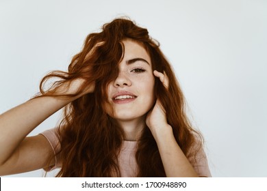 tender young girl looking at the camera and touching her head on a white background