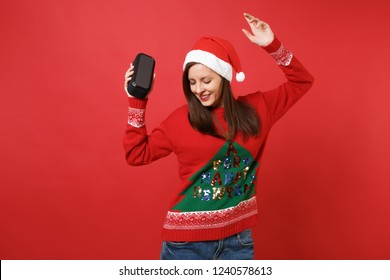 Tender Young Santa Girl Dancing, Rising Hand, Holding Portable Wireless Bluetooth Music Speaker Isolated On Red Background. Happy New Year 2019 Celebration Holiday Party Concept. Mock Up Copy Space