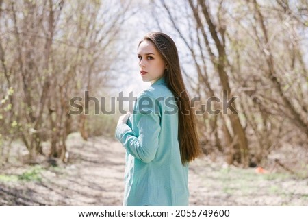 Tender, young woman, in a blue shirt, outdoors in the warm season 