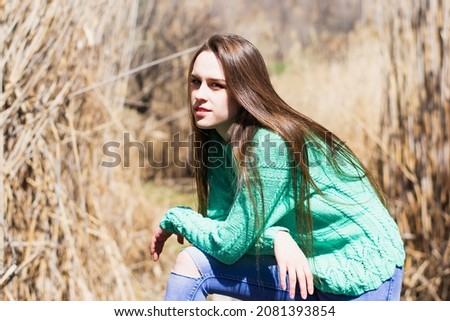 Tender, young woman, in a blue sweater, outdoors in the warm season 