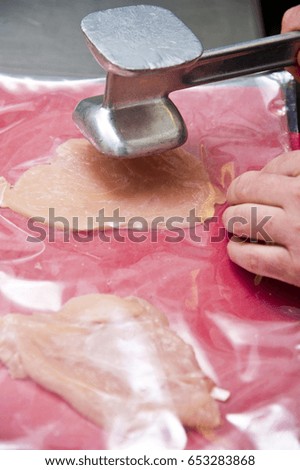 Tenderizing the chicken meat with a mallet - Preparing homemade chicken kiev in a kitchen