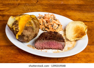 Tenderloin Steak With Twice Baked Potato And Carrot And Raisin Salad On Rustic Wooden Table