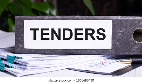 TENDERS is written on a gray file folder next to documents. Business concept