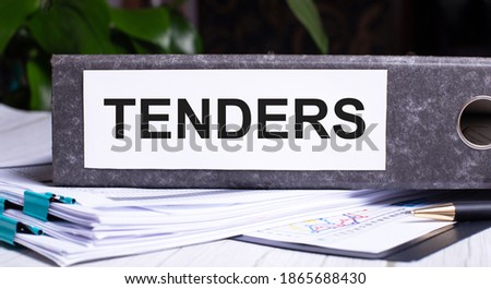 TENDERS is written on a gray file folder next to documents. Business concept