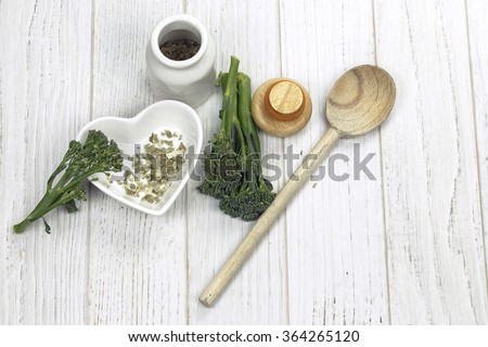 Tender-stem broccoli and herbs on white wooden surface