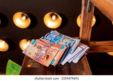 Tenge KZT On A Bright Background With Light Bulbs. Tenge Banknotes. Money Kazakhstan Tenge. A Stack Of Haute Couture With A Large Denomination, Paper Bills In The Photo