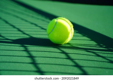 Tennis ball with tennis court and net in background.                                       