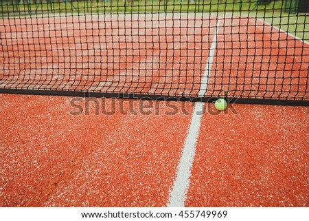 Tennis ball lies next to the net on the tennis court