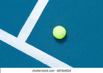 Tennis ball on blue tennis court with white line