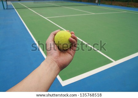 tennis ball on  player hand ,tennis ball on green blue court and net in sport competition background, sport club