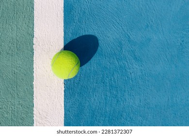 Tennis ball on a white line on hard tennis court of blue color. Flat lay, top view, copy space. Summer sport. Tennis court with a tennis ball close up. Summer activities and active life concept - Powered by Shutterstock