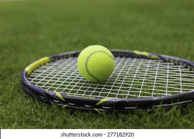 Tennis ball and racket on green grass background