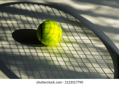 Tennis ball and its shadow on an isolated white background. Tennis ball has tennis racket and net shadow on it. Sport, tennis concept.