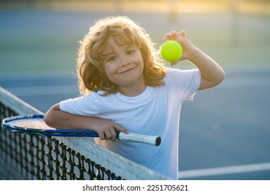 Tennis child. Kid with tennis racket and tennis ball playing on tennis court. - Powered by Shutterstock