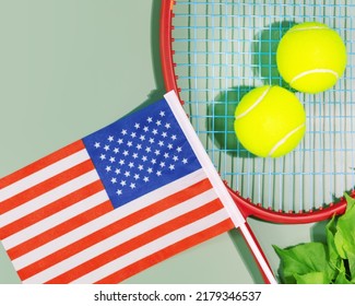 Tennis Competition In The USA. Sport Composition With Yellow Tennis Balls, Red Racket And The Flag Of America On A Green Background. US Open. Flat Lay