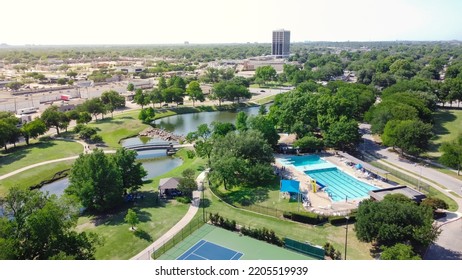 Tennis court and swimming pool sport complex in recreation park with small pond and downtown Richardson, Texas in background. Mature green trees along the trails in summertime - Shutterstock ID 2205519939