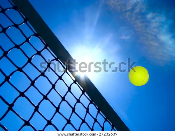 Tennis game concept with ball flying over the net\
under the blue sky.