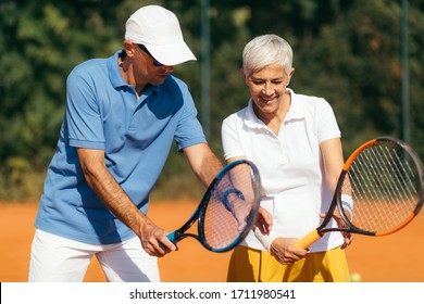 Tennis Instructor with Senior Woman on Clay Court. Woman having a Tennis Lesson. - Powered by Shutterstock