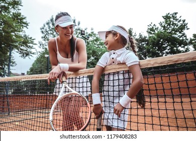 Tennis instructor with young girl on tennis training. female tennis instructor and child on court leaned on the net - Powered by Shutterstock