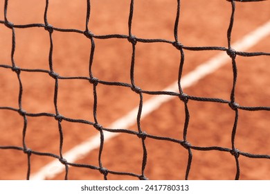 Tennis net. Close-up view of the nodes of a sports net against the background of a court with a ground surface - Powered by Shutterstock