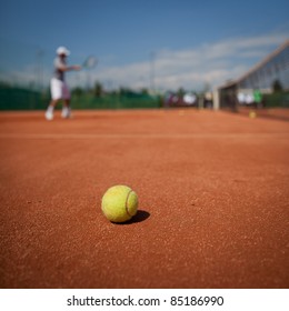 Tennis player in action on tennis court (selective focus, focus on ball in the foreground)