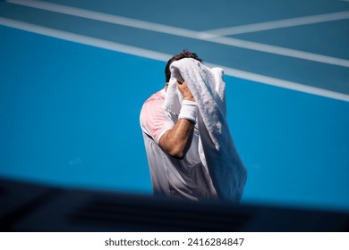 tennis player drying off with a towel on a tennis court in summer - Powered by Shutterstock