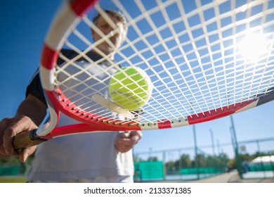 Tennis Player Holding Tennis Ball On Racket Against Blue Sky