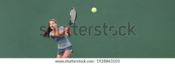 Tennis player\
playing game on outdoor hard court banner. Athlete Asian woman\
hitting ball with racket during match panoramic header. on green\
banner. Sports in\
competition.