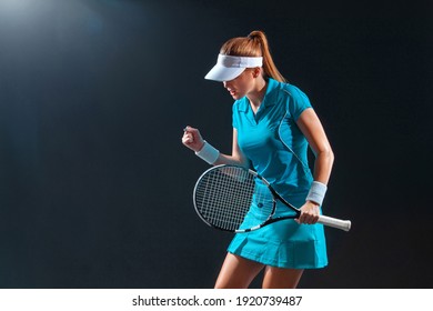 Tennis player with racket in blue costume. Woman athlete playing on black background.