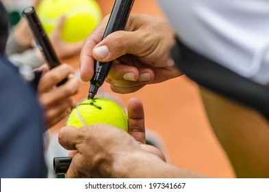 Tennis Player Signs Autograph On A Tennis Ball After Win, Closeup Photo Showing Tennis Ball And Hands Of A Man Making Signature.