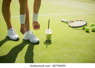 Tennis player tying sports shoes before the practice - Powered by Shutterstock