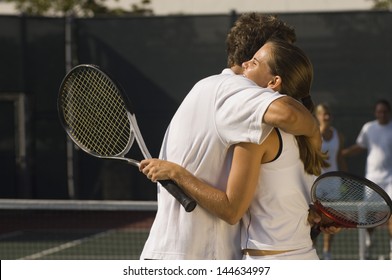 Tennis Players holding rackets Hugging at Net side view - Powered by Shutterstock